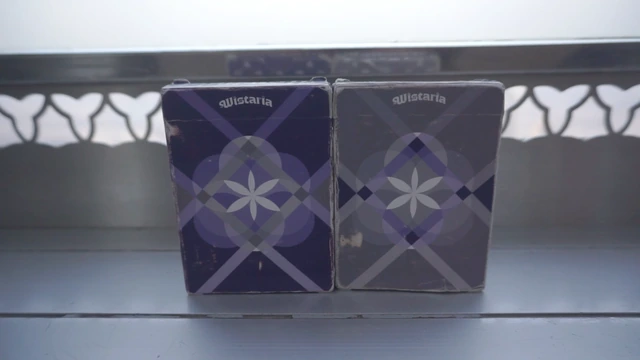 Purple and grey printed Wistaria boxes on a windowsill, showing the actual surfaces and central flower emblems